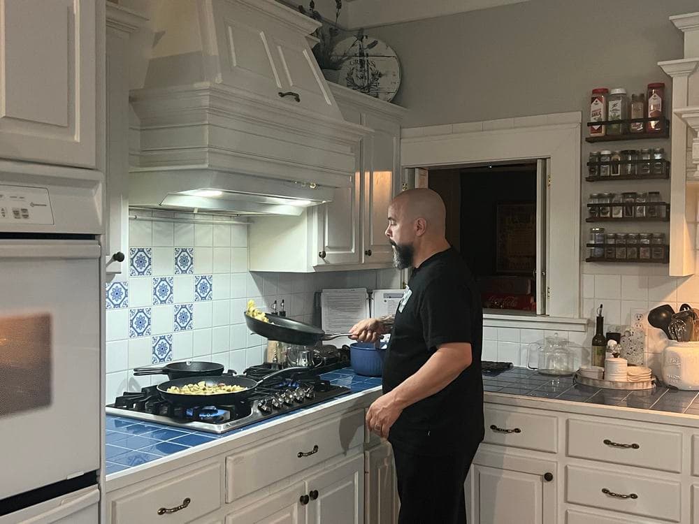 A man cooks on a stove in a bright, modern kitchen.