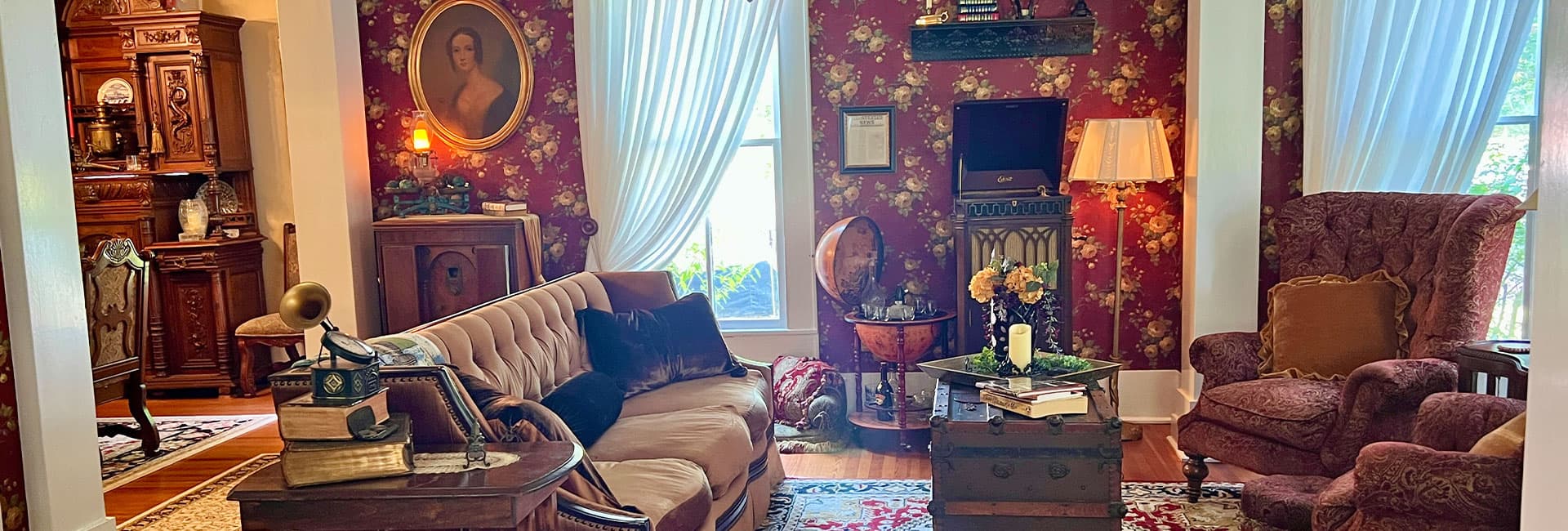 A vintage living room featuring floral wallpaper, antique furniture, and a cozy atmosphere.